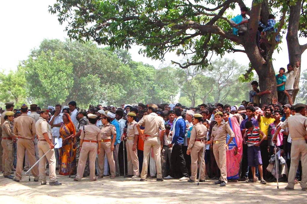 Indian policemen cordon off the area as villagers and others look toward the tree where two teenage girls were found hanging in the Katra village in the northern Indian state of Uttar Pradesh. Photo: AP