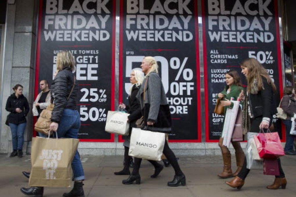 Shoppers walk past Black Friday advertising in shop windows on Oxford Street, central London. Photo: AFP