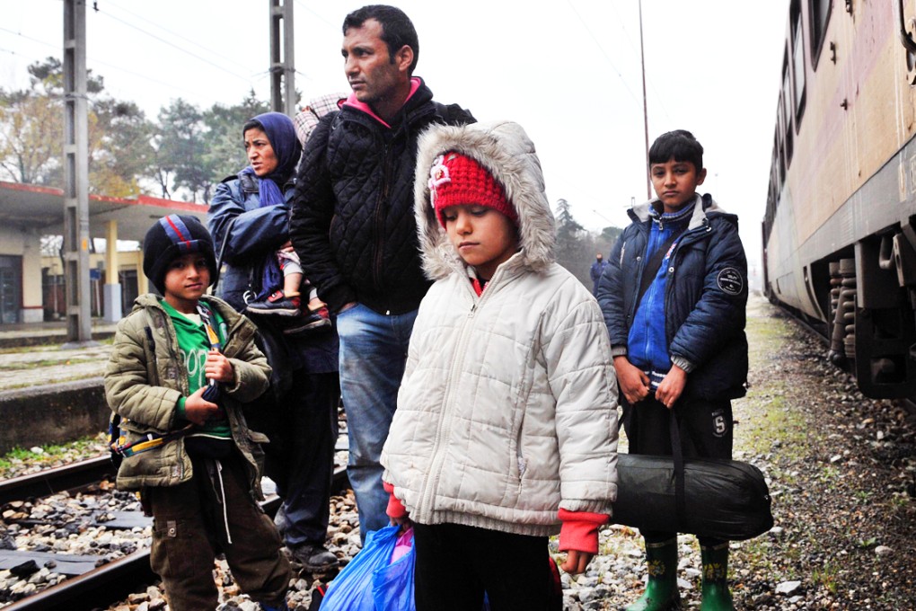 A family from Afghanistan standing at the border post of Idomeni, some 600 km North of Athens, on the border Greece-Macedonia. Photo: AFP