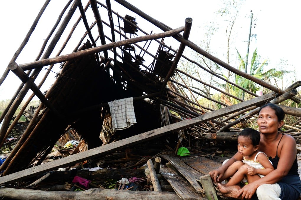 A mother and her child sits next to their house destroyed at the height of Typhoon Hagupit at a village along a highway in San Julian, eastern Samar. Photo: AFP