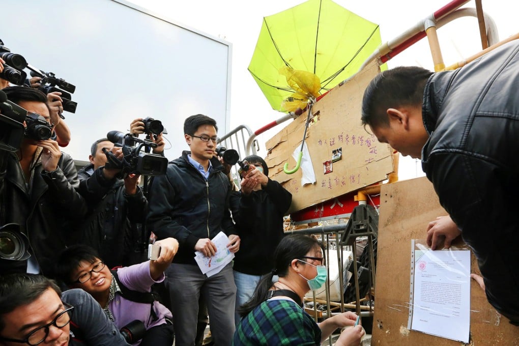 Bus company representatives post copies of a court injunction in Admiralty, authorising bailiffs to clear protesters. Photo: Sam Tsang