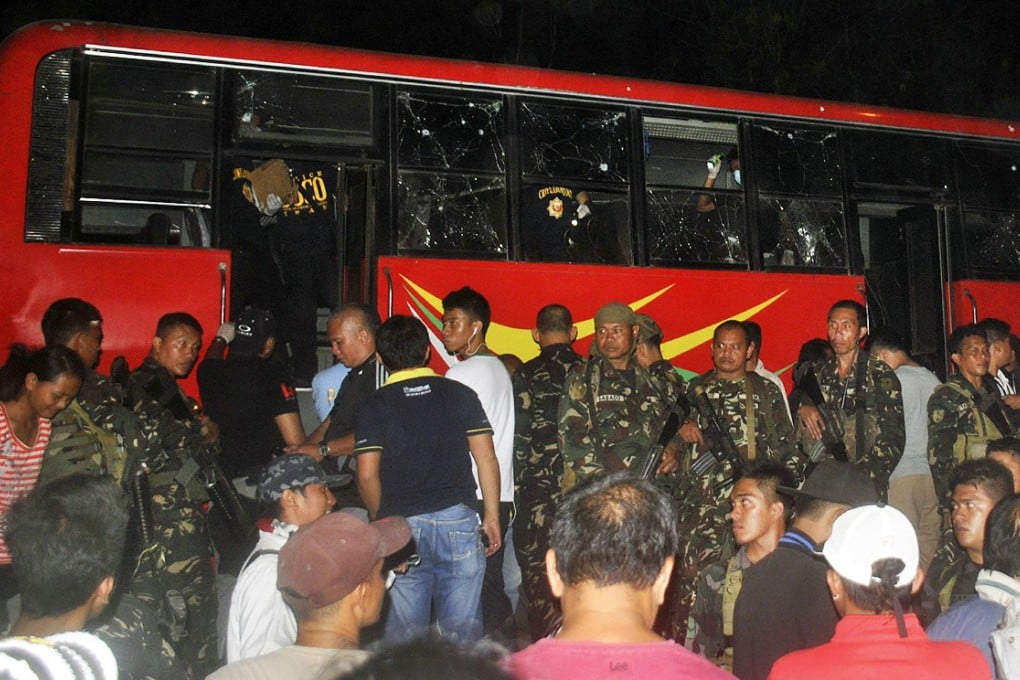 Rescuers examining a damaged passenger bus at the site of a bomb attack in Maramag town in Bukidnon province. Photo: EPA