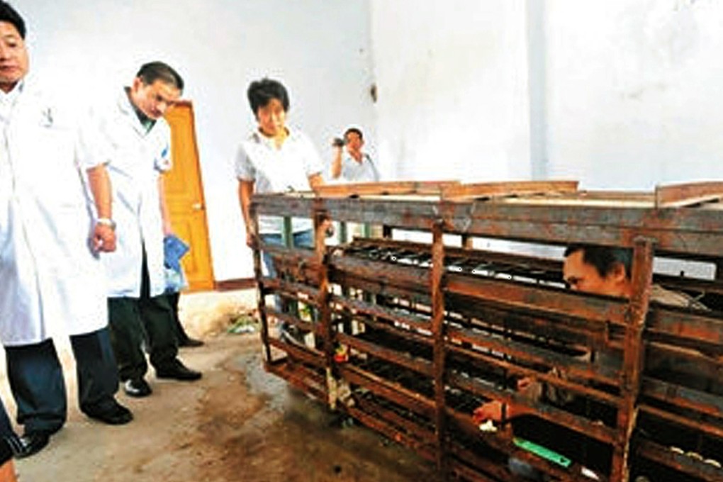 Doctors view the cage Wang Dafeng had been kept in. Photo: The Beijing News