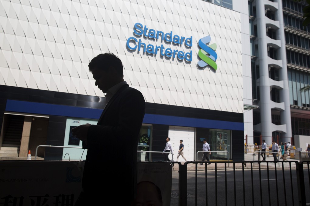 A pedestrian walks past a Standard Chartered Plc bank branch in the Central business district of Hong Kong, China, on Monday, Oct. 13, 2014.  Photo: Reuters