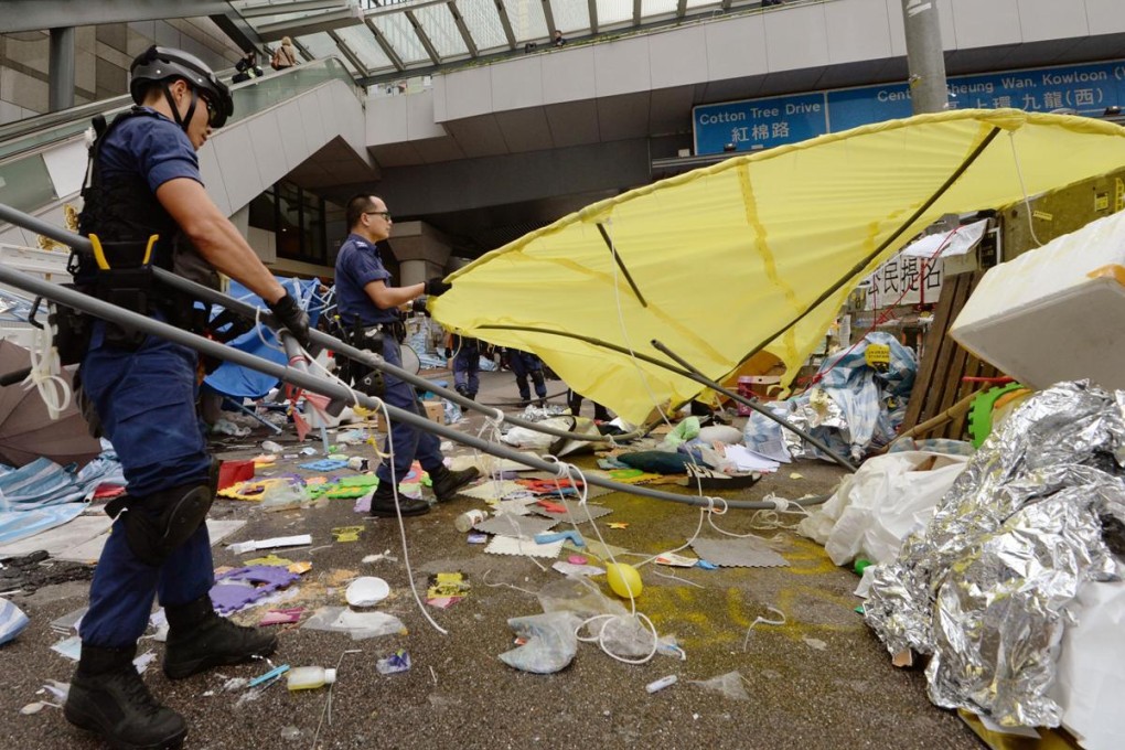 Police officers clear a large yellow umbrella at the Occupy site in Admiralty. Photo: Kyodo