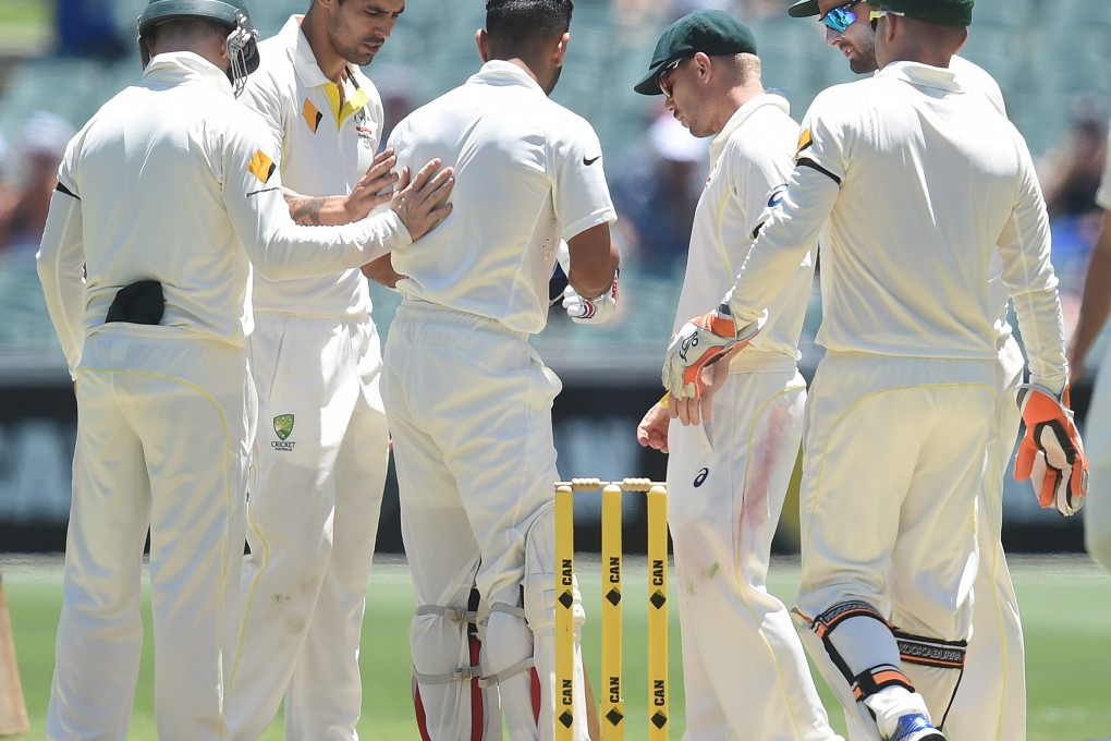 Australian cricketers tend to Indian batsman Virat Kohli (centre) after he was struck by a ball from Australian bowler Mitchell Johnson (second left) at the Adelaide Oval.  Photo: EPA