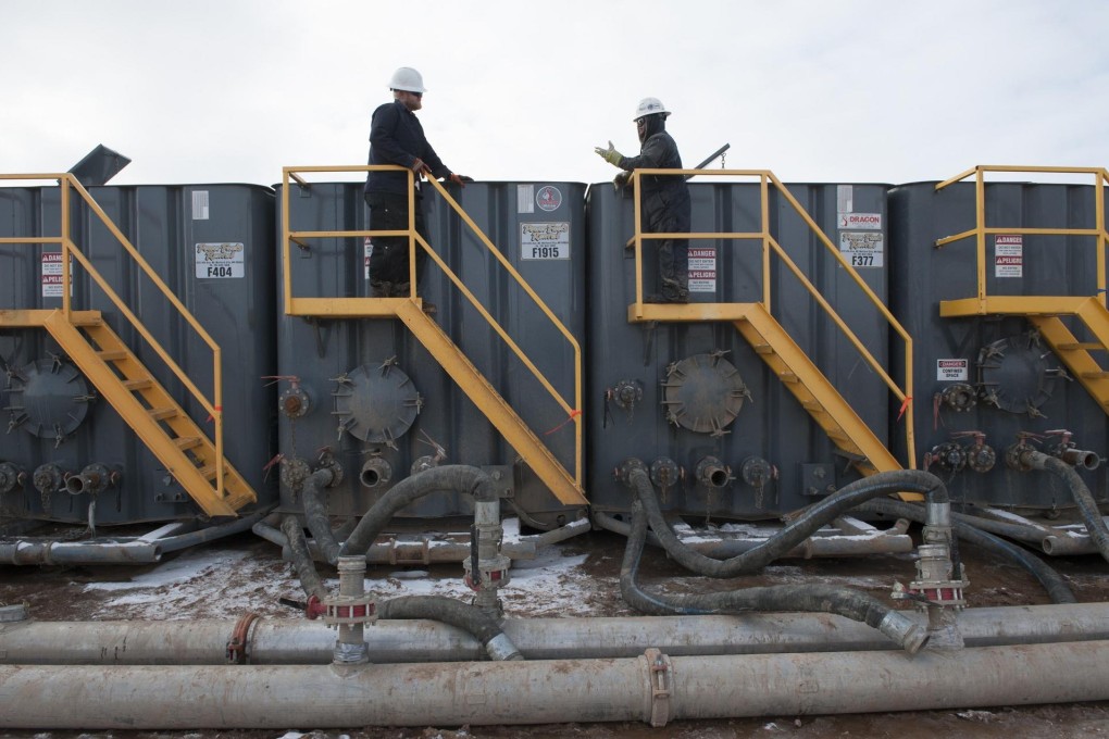 Workers monitor water tanks at a fracking site in North Dakota.