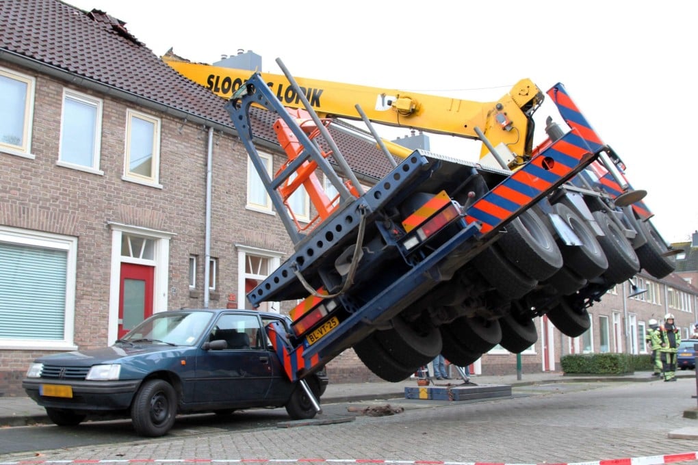 A truck hangs in the air after the crane toppled over onto the house in Ijsselstein. Photo: EPA
