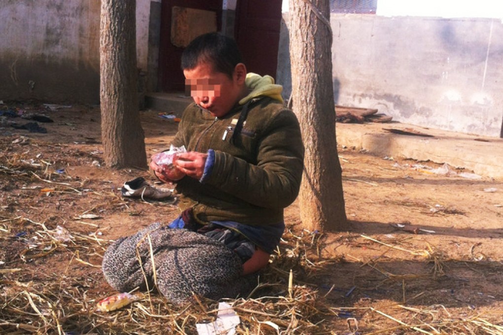 A child eats while tethered to a tree with rope in the shelter's backyard. Photos: Weibo
