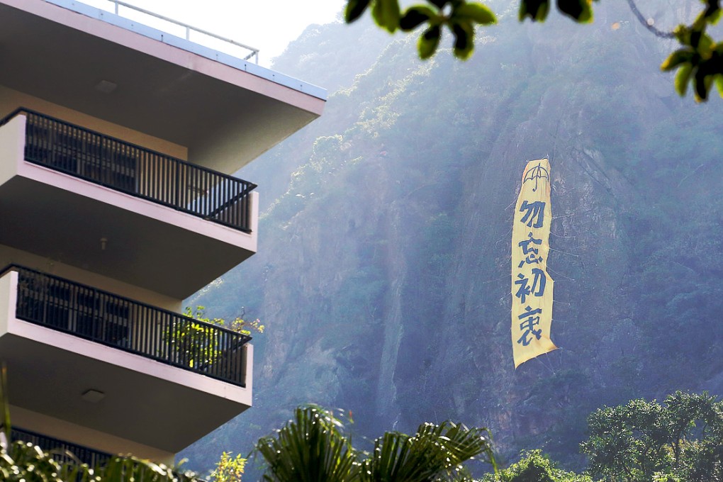 A new banner calling for people not to forget the goals of Occupy hangs on a vertical face at Victoria Peak: Photo: Felix Wong