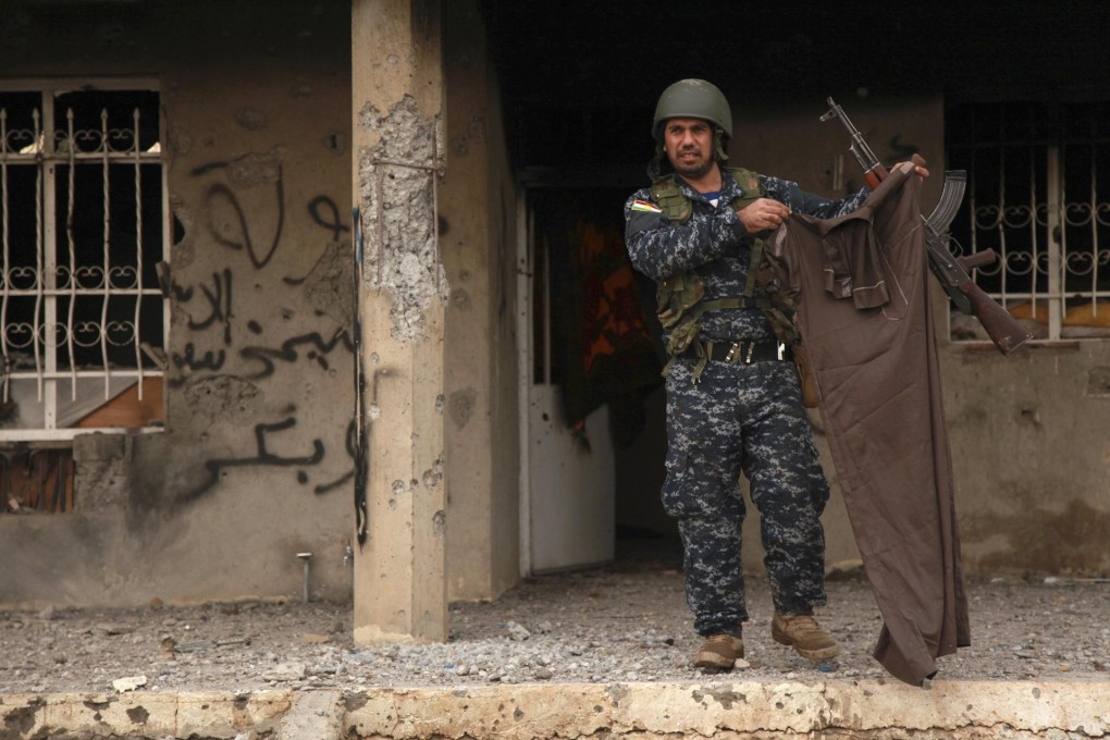 A Kurdish fighter holds an IS fighter's item of clothing. Photo: Reuters