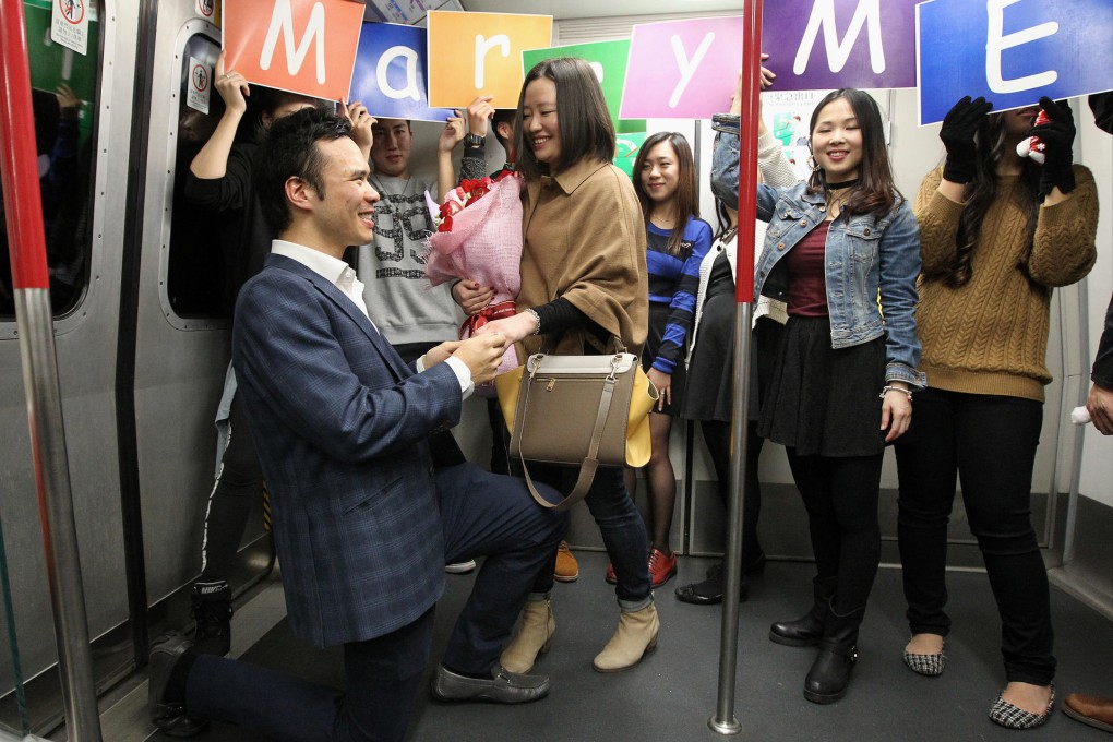 Richard Chou (left) proposes on one knee to Miranda Chen (centre) aboard an MTR train on the Island Line. Photo: Edward Wong