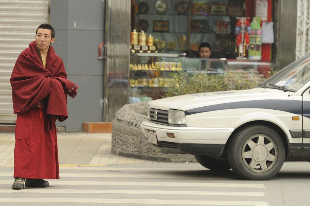 A Tibetan monk walks past a police car on a street in Chengdu, Sichuan province in this file picture from January 2012. Photo: AFP