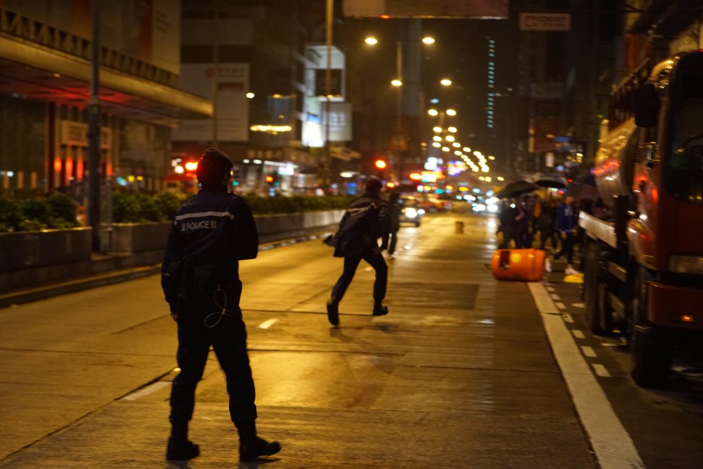 Police chase after a protester who had knocked over trash bins on Nathan Road. Photo: Vic Shing