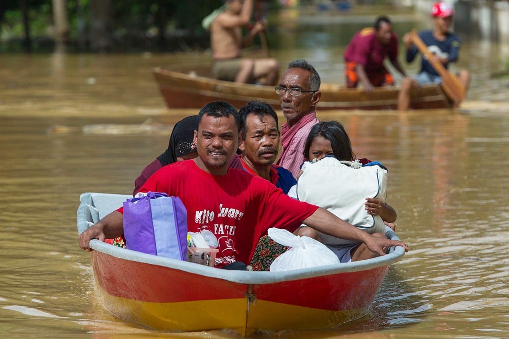 A family ride on a boat through floodwater in Pengkalan Chepa, near Kota Bharu on Friday. Photo: AFP
