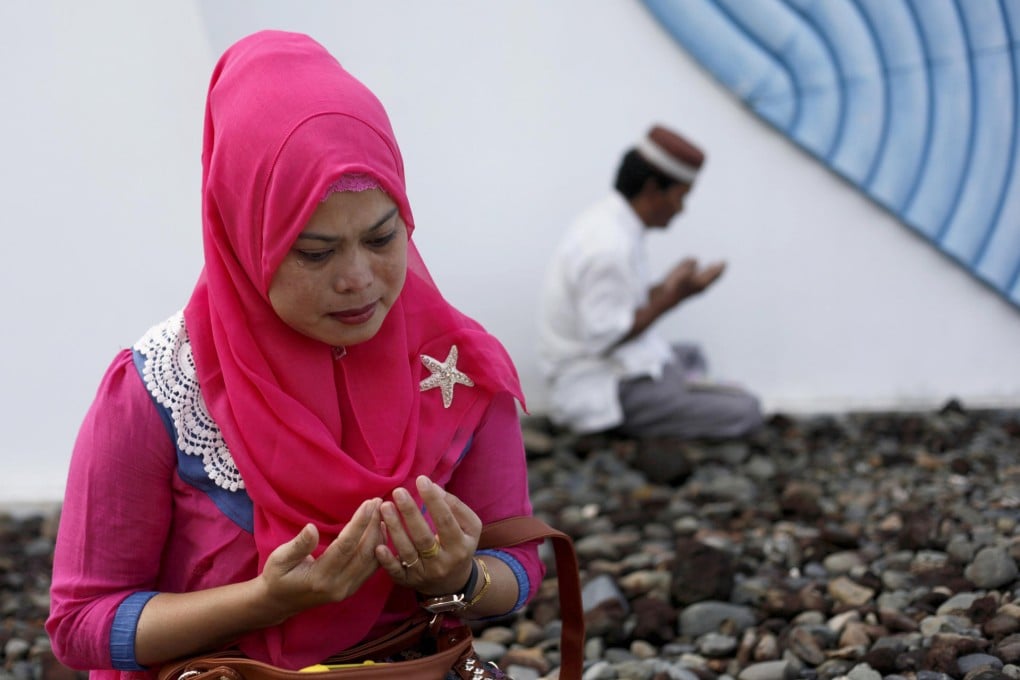 A woman prays at a mass grave of tsunami victims during yesterday's 10th anniversary commemoration in Aceh Besar, Indonesia. Photo: AP