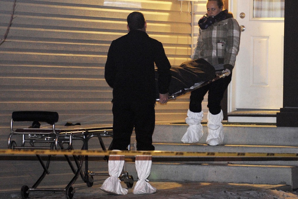 Members of the coroner’s office remove a body from one of three crime scene in north Edmonton. Photo: Reuters