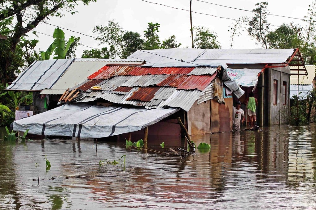 A resident of Samar province looks out from his home sitting in floodwaters brought on by heavy rains. Photo: Reuters