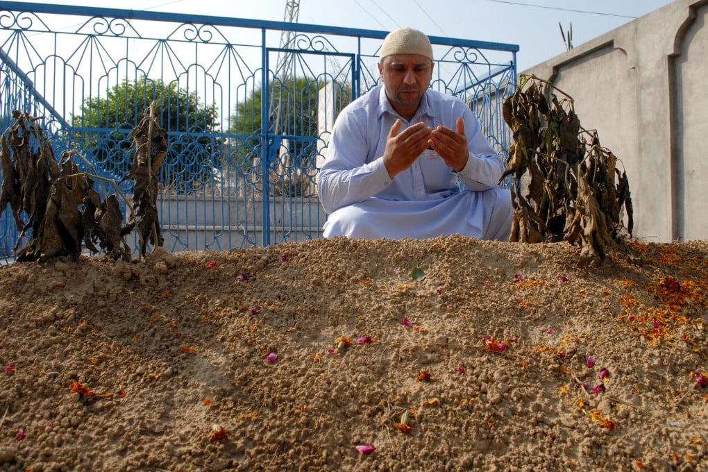 Shakeel Hussain, eldest son of Jumma Khan, prays at the grave of his father in Mirpur. Photo: AFP