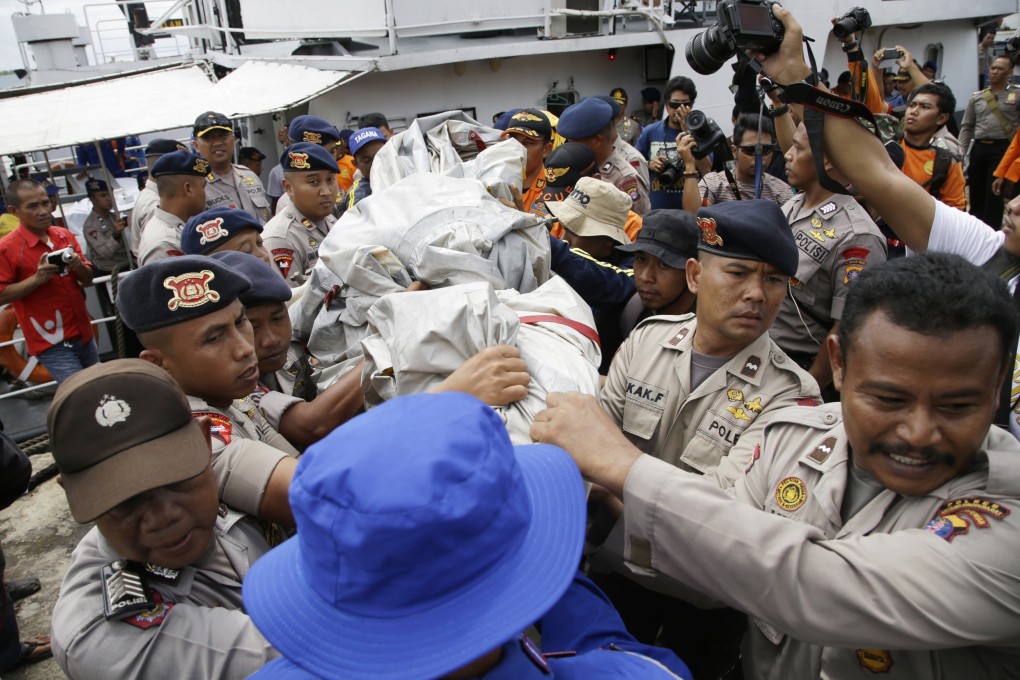 Indonesian police carry parts of an airplane recovered from the sea to a holding point at the port of Pangkalan Bun. Photo: AP