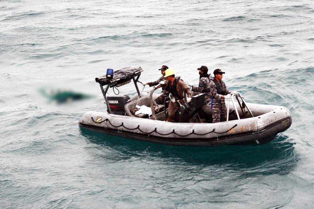 Indonesian Navy personnel in a rubber dinghy recovering a body believed to be a victim of the crashed AirAsia airplane. Photo: EPA