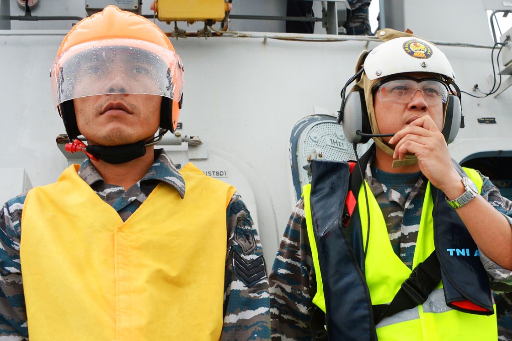 Two Indonesian officers from navy vessel KRI Bung Tomo guide a helicopter at sea on Thursday. Photo: AFP