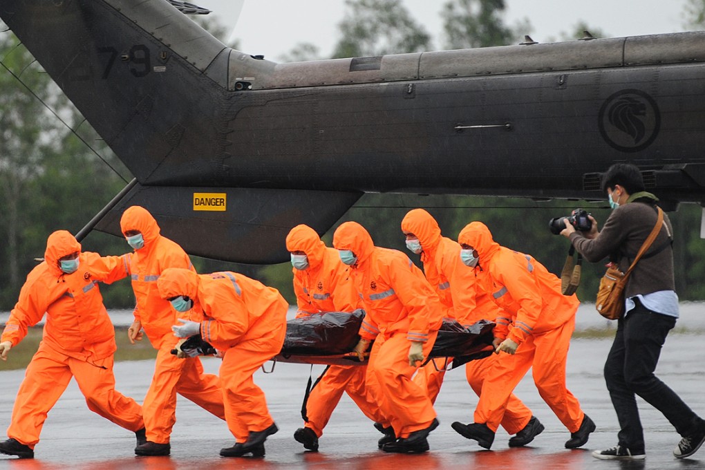 Search and rescue personnel carry a body bag containing a victim of the crashed AirAsia flight QZ8501 at Iskandar Air Base, Pangkalan Bun on Sunday. Photo: Xinhua