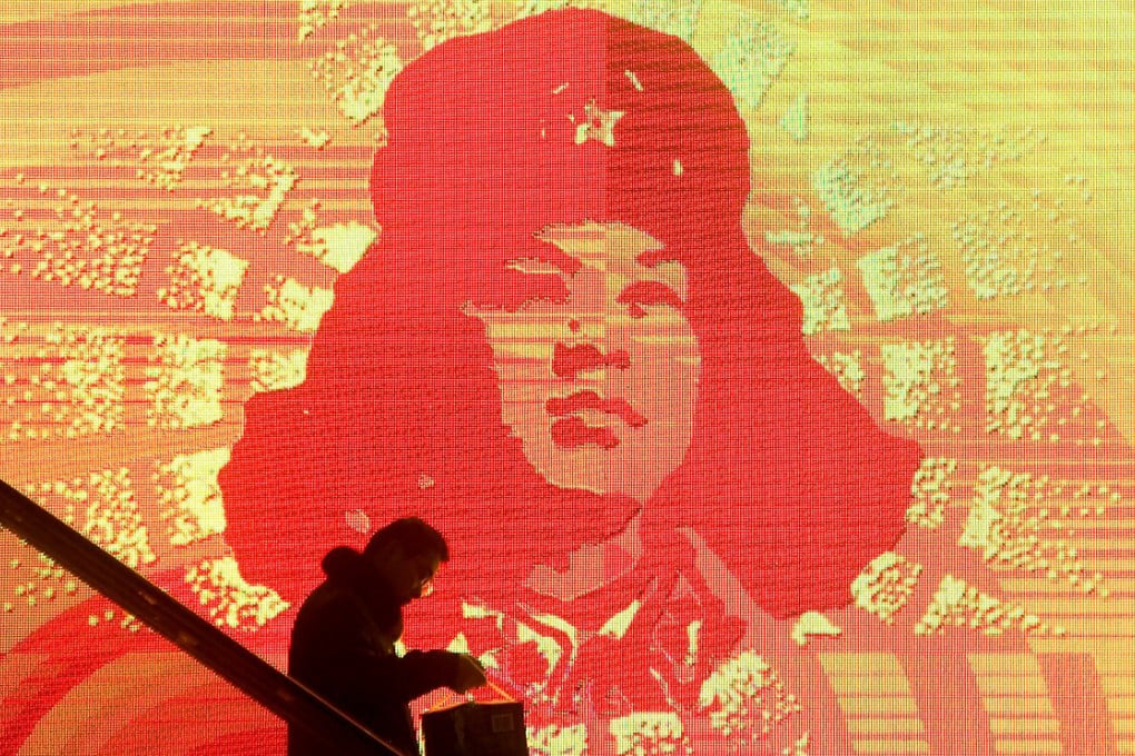 A Chinese passenger on an escalator is passing by a portrait of Chinese role model Lei Feng on a large screen in China's Shandong province. Photo: EPA