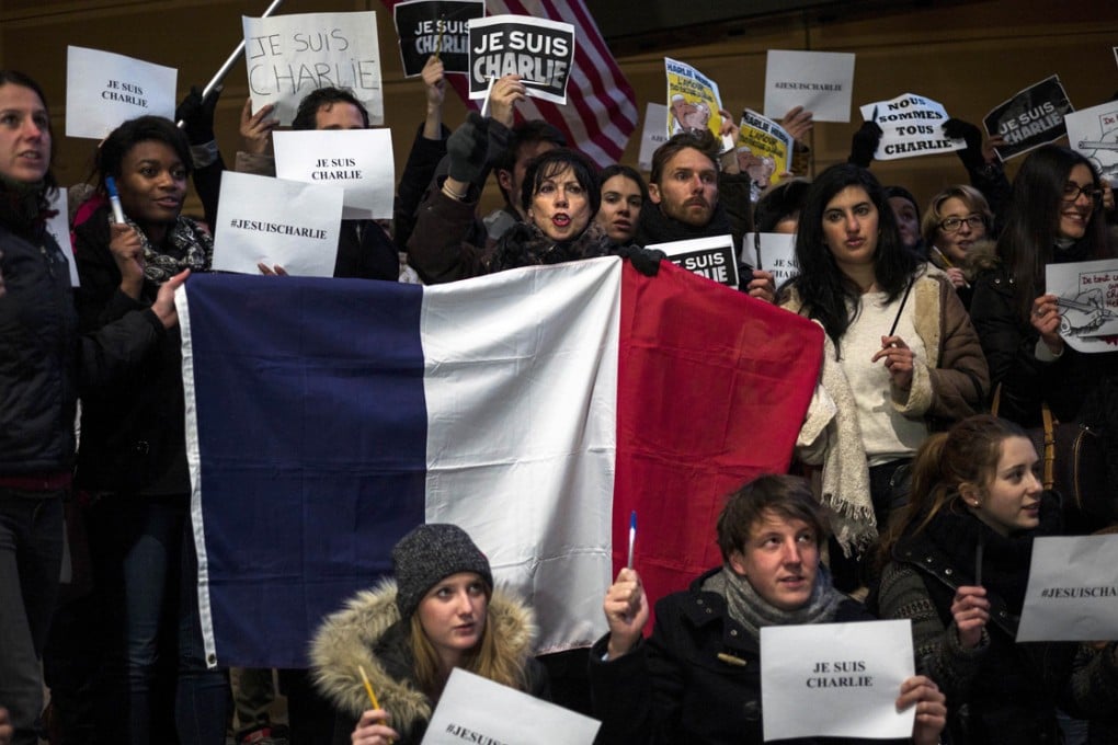 US citizens hold the French national flag and posters with the words "Je Suis Charlie" outside the Newseum in Washington on Wednesday in solidarity with the victims of the shooting at the Paris office of the satirical publication Charlie Hebdo. Photo: AFP