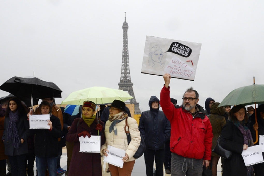 A man holds a sign reading "Je suis Charlie" (I am Charlie) as people observe a minute of silence in front of the Eiffel Tower in Paris. Photo: AFP