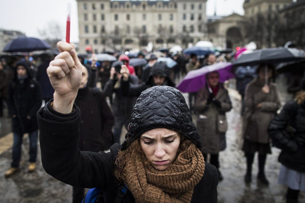 A woman holds a pencil aloft in Paris. Photo: EPA