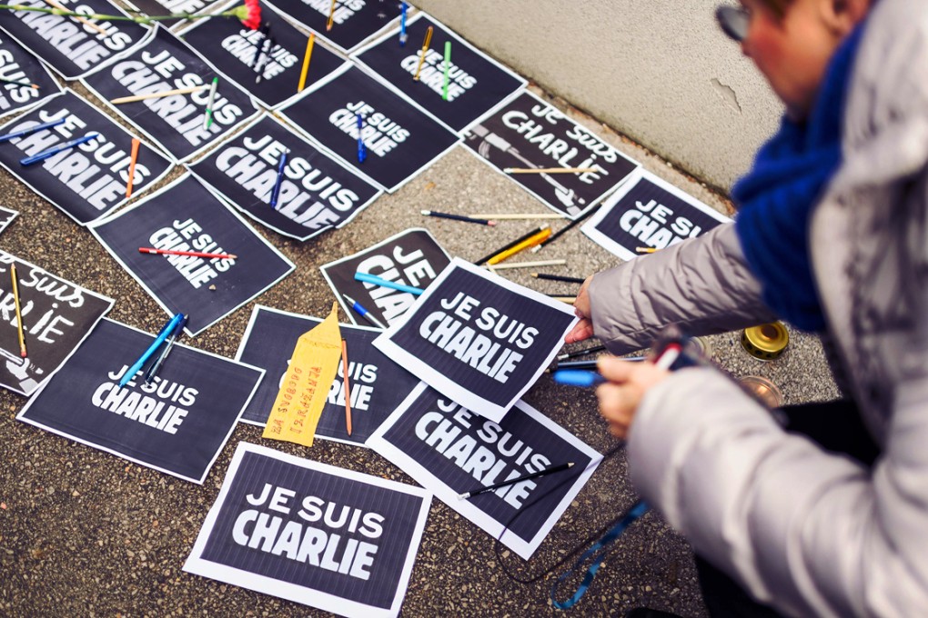 A woman lays a pen and placard reading in French "I am Charlie" in front of the French embassy during a gathering in tribute of victims of the attack on French satirical weekly Charlie Hebdo. Photo: AFP