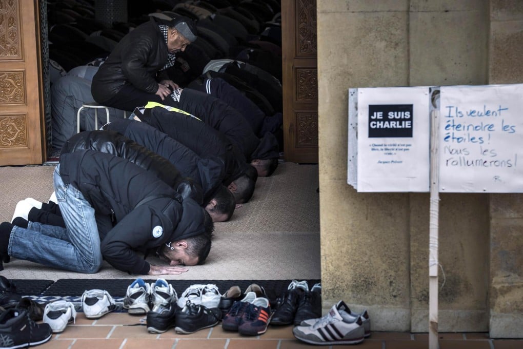 French Muslims pray by a sign reading "Je suis Charlie". Photo: AFP