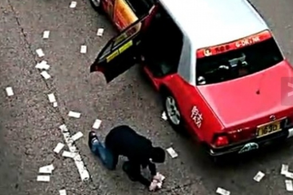 A man picks up money spilled by a security van in Wan Chai on December 24. More than HK$7 million is still missing. Photo: SCMP Pictures