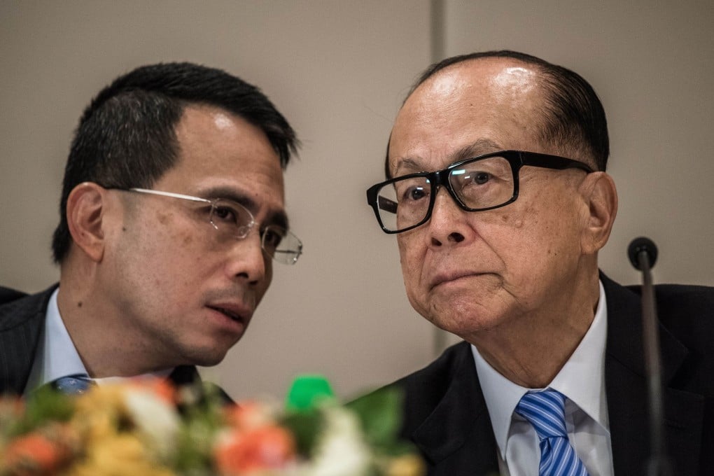 Li Ka-shing (right) listens to his son Victor Li Tzar-kuoi during a press conference in Hong Kong on Friday to announce the company reorganisation.