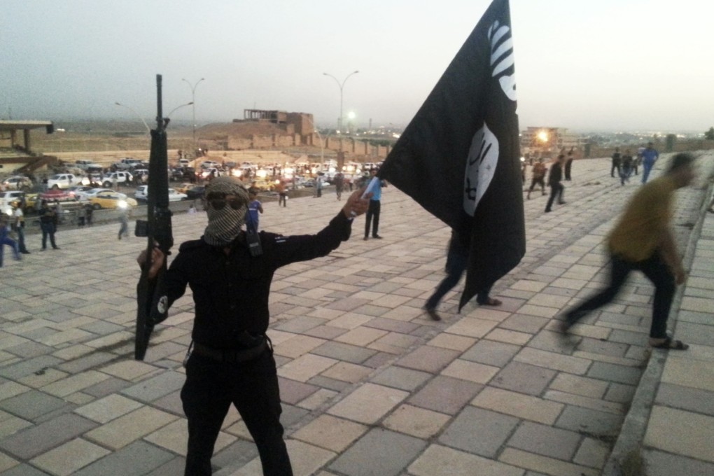 A fighter of the Islamic State waves an IS flag on a street in the Iraqi city of Mosul. Some young Malaysian men see joining IS as a way to 'cleanse their sins'. Photo: Reuters