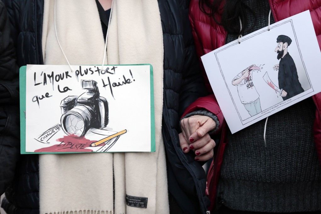 People at the Paris rally hold up cartoons, including one reading "Love is stronger than hate". Free speech is a balancing act. Photo: AFP