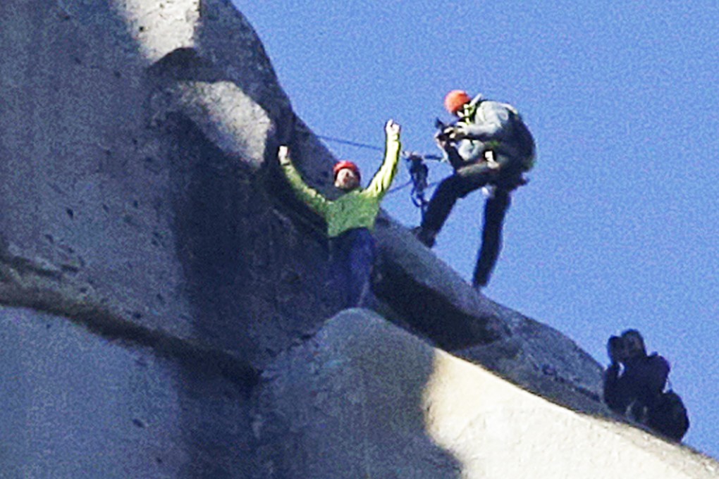 Tommy Caldwell raises his arms after reaching the summit of the Dawn Wall of El Capitan on Wednesday, as seen from the valley floor in Yosemite National Park. Photo: AP