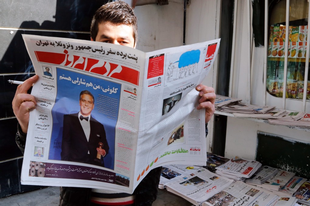 An Iranian man reads a copy of the January 13 edition of the reformist daily newspaper "Mardom-e Emrooz" featuring a photo of George Clooney with a headline reading "I am Charlie, too". Photo: EPA