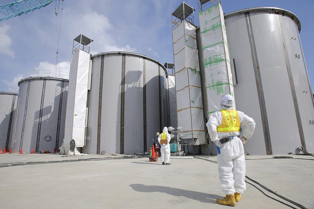 A worker wearing protective clothing looks up at welding storage tanks for radioactive water at the tsunami-crippled Fukushima Daiichi nuclear plant. Photo: EPA