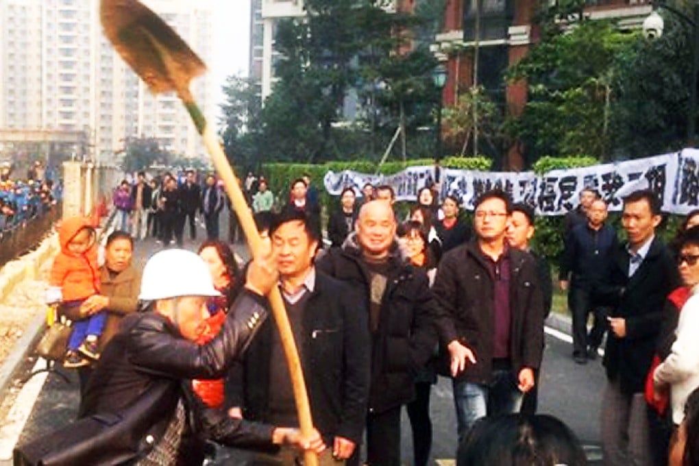 A building worker threatens residents with a shovel during yesterday's clashes. Photo: China National Radio