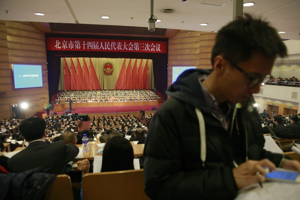 A journalist browses his smartphone as Beijing Mayor Wang Anshun reads a work report on stage during an opening session of the 14th Beijing Municipality People's Congress. Photo: AP