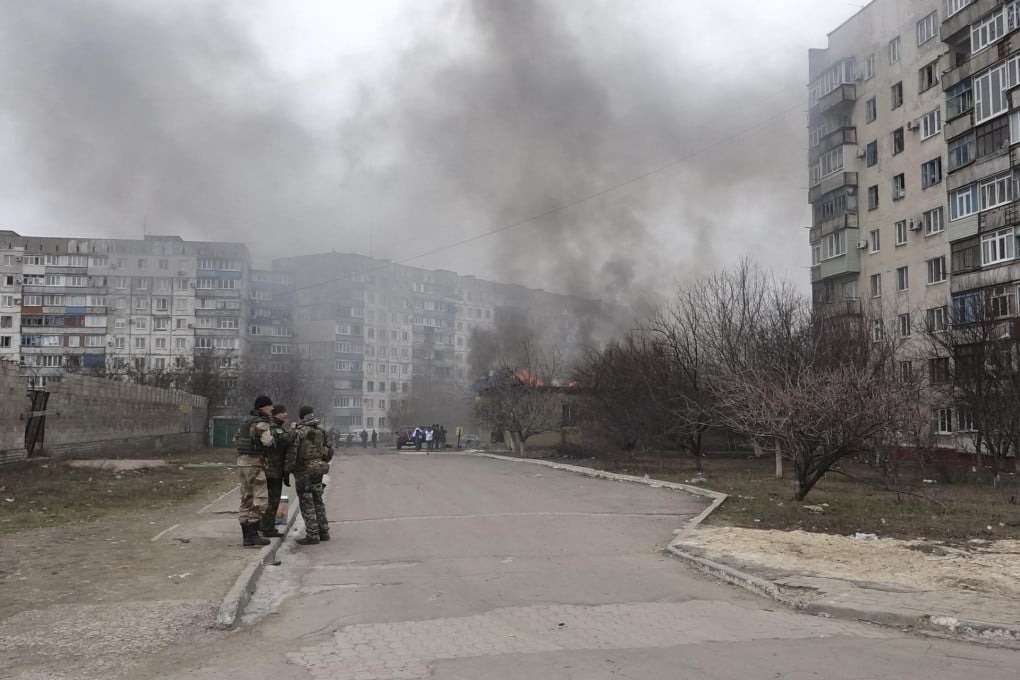 Troops stand guard amid burning residential buildings in Mariupol in eastern Ukraine following the devastating rocket attack. Photo: Reuters