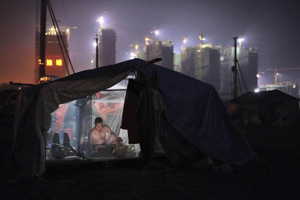 A worker uses a laptop inside his dormitory near a construction site in Hefei. By some measures, China is still a relatively poor developing economy. Photo: Reuters