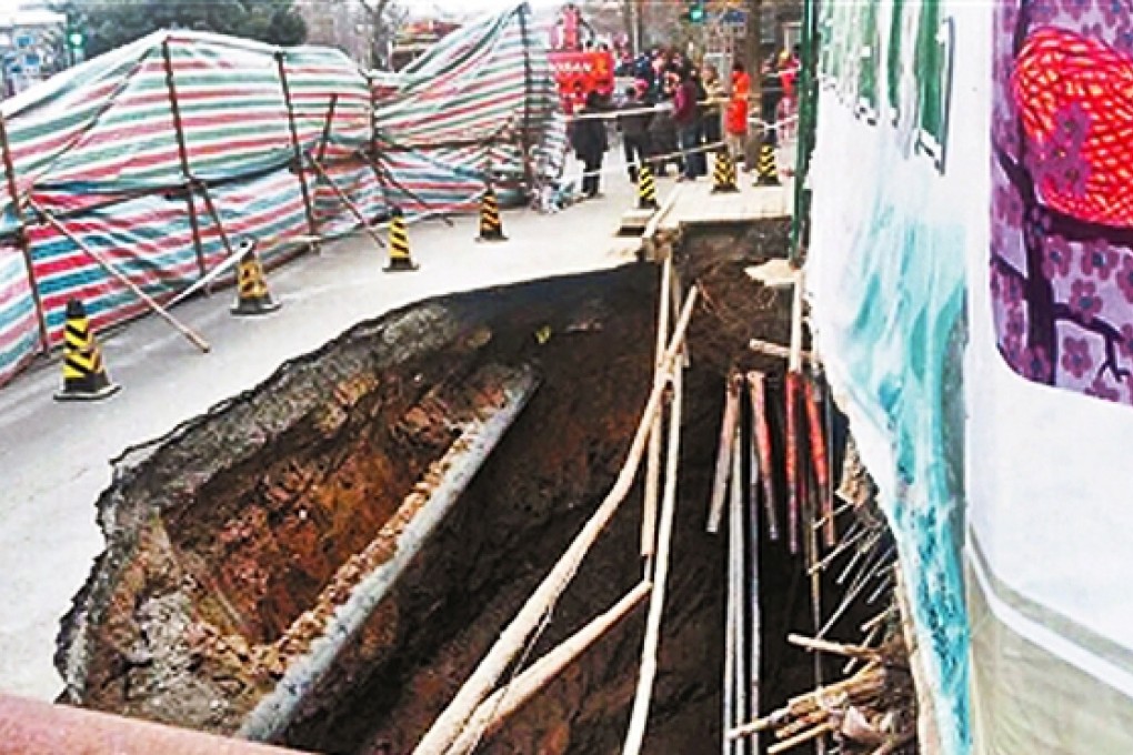 Workmen tried twice - and failed both times - to fill a large hole that kept appearing in the street beside a building in Deshengmen Inner Street, Beijing early on Saturday. Photo: China News
