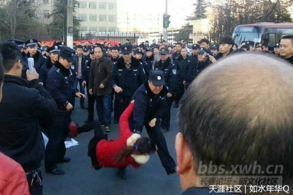 The photo shows a policeman lifted a woman by the collar and threw her on the pavement as dozens of fellow officers watched.