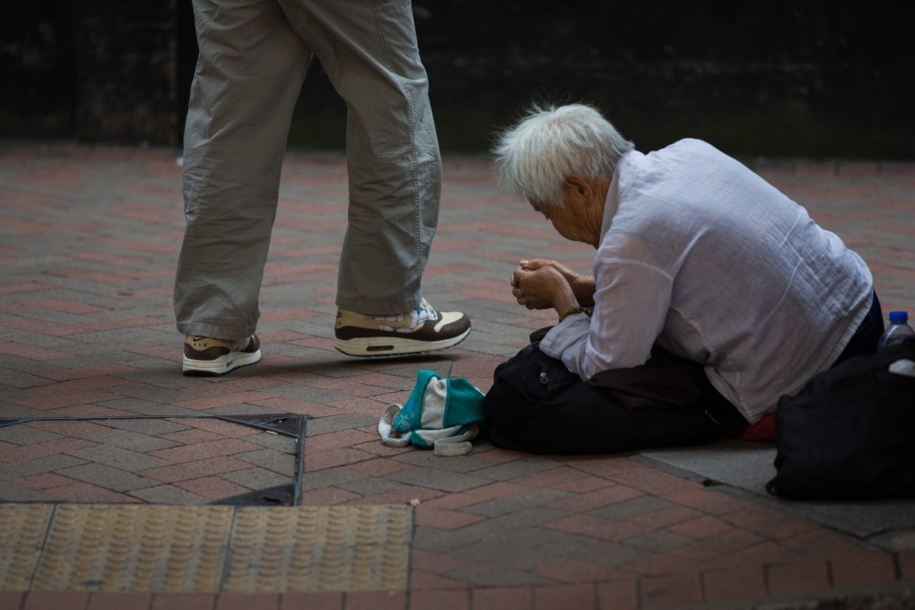 A pedestrian walks past a woman begging for money in Hong Kong where a fifth of the population is living in poverty. A wealth gap created in part by those with connections and those with not is becoming an issue in China. Photo: Bloomberg