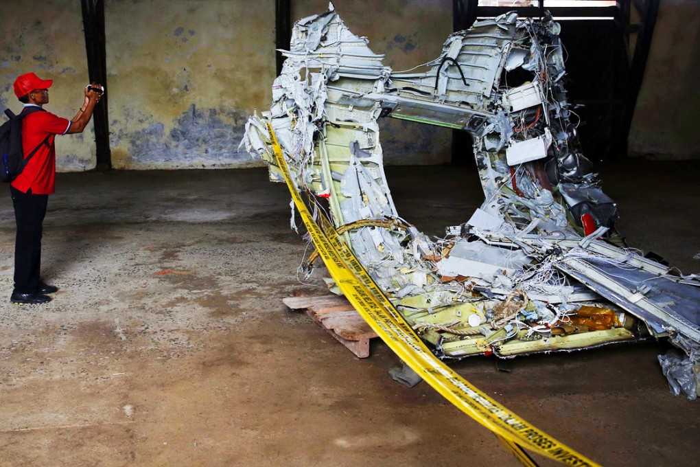 A man shoots video footage of part of the fuselage of crashed AirAsia Flight QZ8501 inside a storage facility at Kumai port in Pangkalan Bun. Photo: Reuters