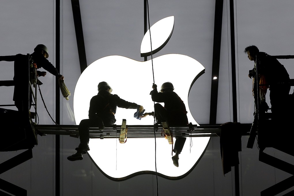 The Apple logo looms behind workers at a store in China as the iPhone giant reported record quarterly sales due to its strong performance in the US and China markets. Photo: Reuters