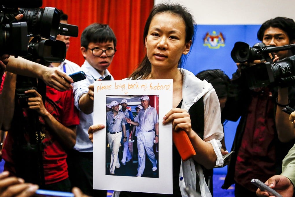 The wife of a missing Malaysia Airlines Flight MH370 passenger shows her husband's picture to reporters at a media conference room in Putrajaya, Malaysia. Photo: EPA